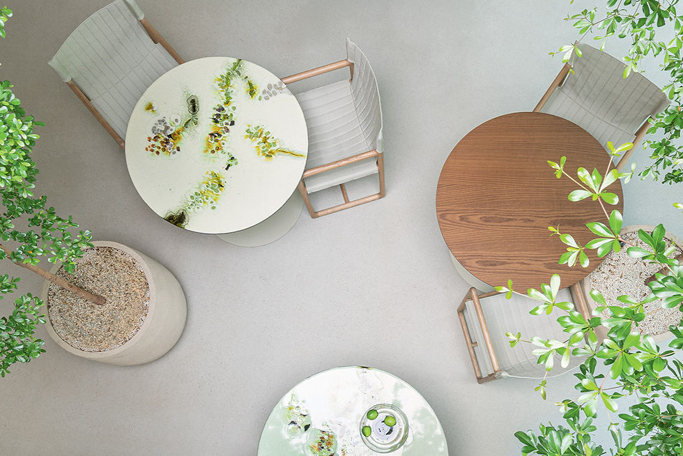 Three round tables with artistic patterns, surrounded by chairs, viewed from above. Potted plants add greenery on a light floor.
