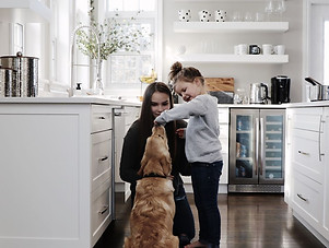 Young children practicing commands in a white luxury kitchen.
