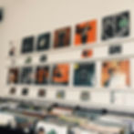 A record store showing shelves with various records and records on a white wall.
