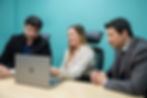 a meeting in boardroom with three colleagues looking at a laptop