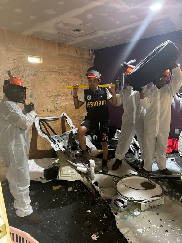 Participants pose for a photo while carrying tools & tire after breaking items at Maximum Rage LLC rage room in Humble near Houston, TX.