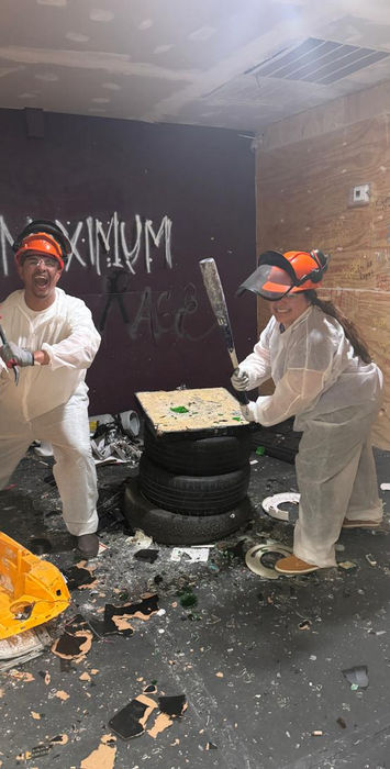 Couple pose for a photo while holding a baseball bat and crowbar after breaking items at the Maximum Rage LLC rage room in Humble TX.