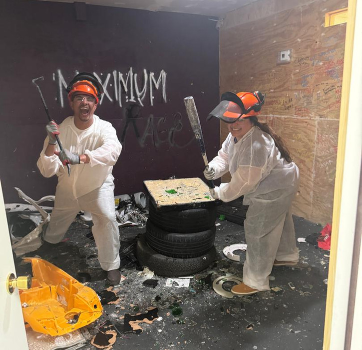 Couple pose for a photo while holding a baseball bat and crowbar after breaking items at the Maximum Rage LLC rage room in Humble TX.