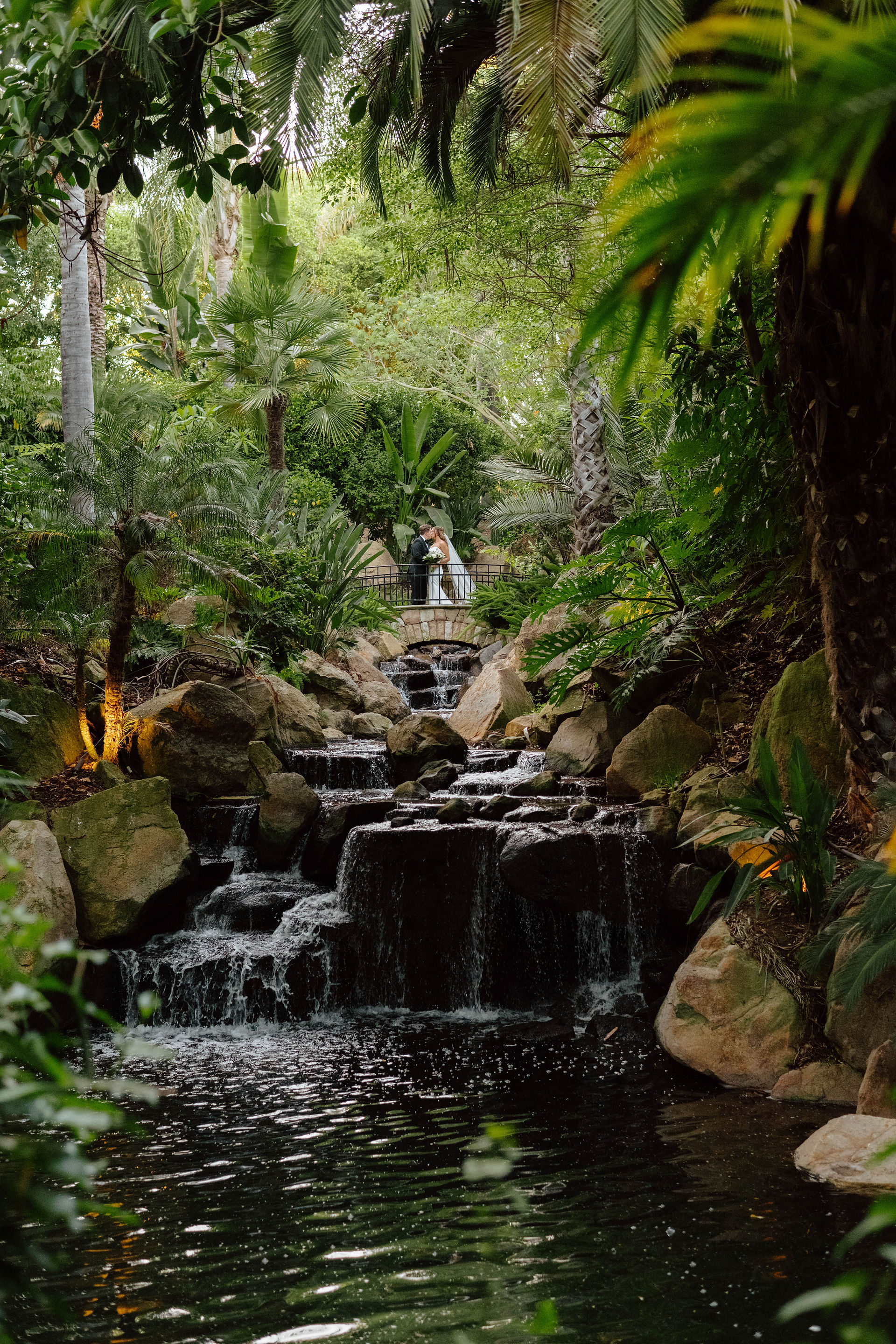 Bride and groom portrait with waterfalls and tropical plants surrounding