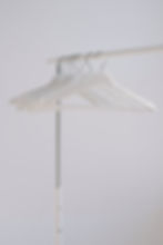 Minimalist white hangers against a white background, representing professional website design services for retail and online shopping platforms.