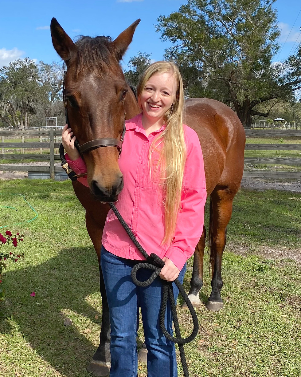 sabrina smiling and posing while caressing the face of a horse
