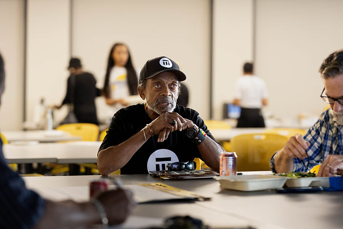 Man in black cap seated at a table with resource materials