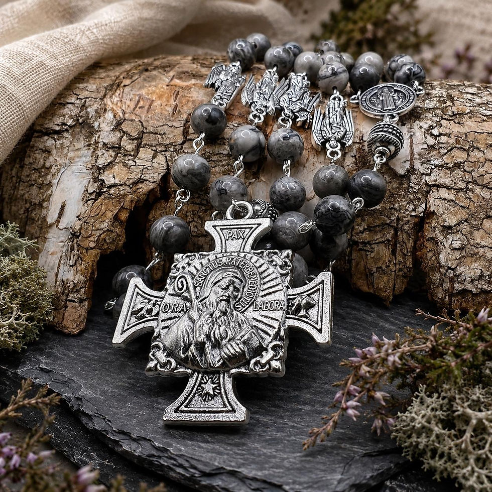 Saint Benedict and Archangels rosary with grey beads and silver-tone cross on slate beside bark