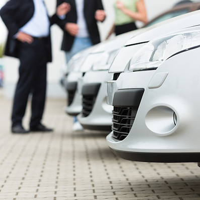 Close-up of three parked silver cars on a paved lot.