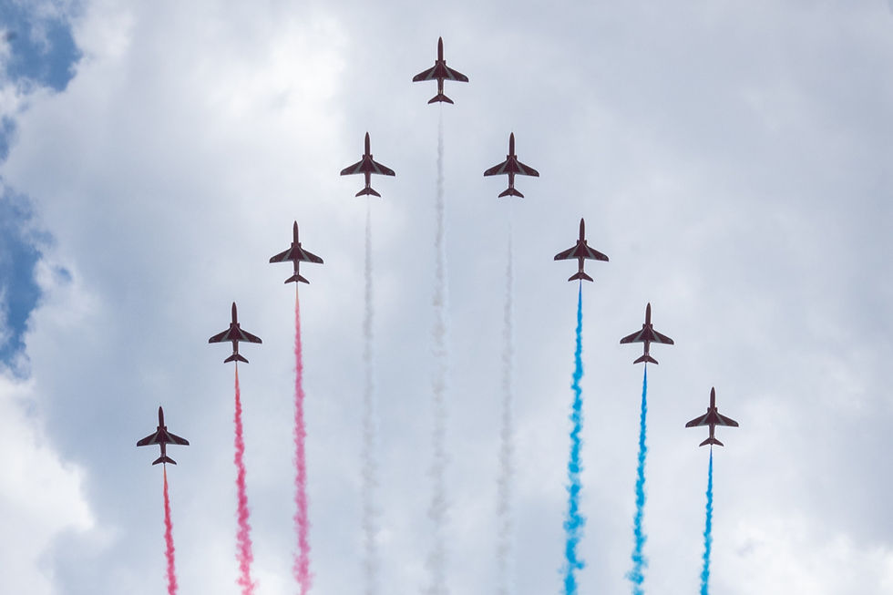 A silhouette of the Red Arrows flying in a 'v' formation against a cloudy sky.