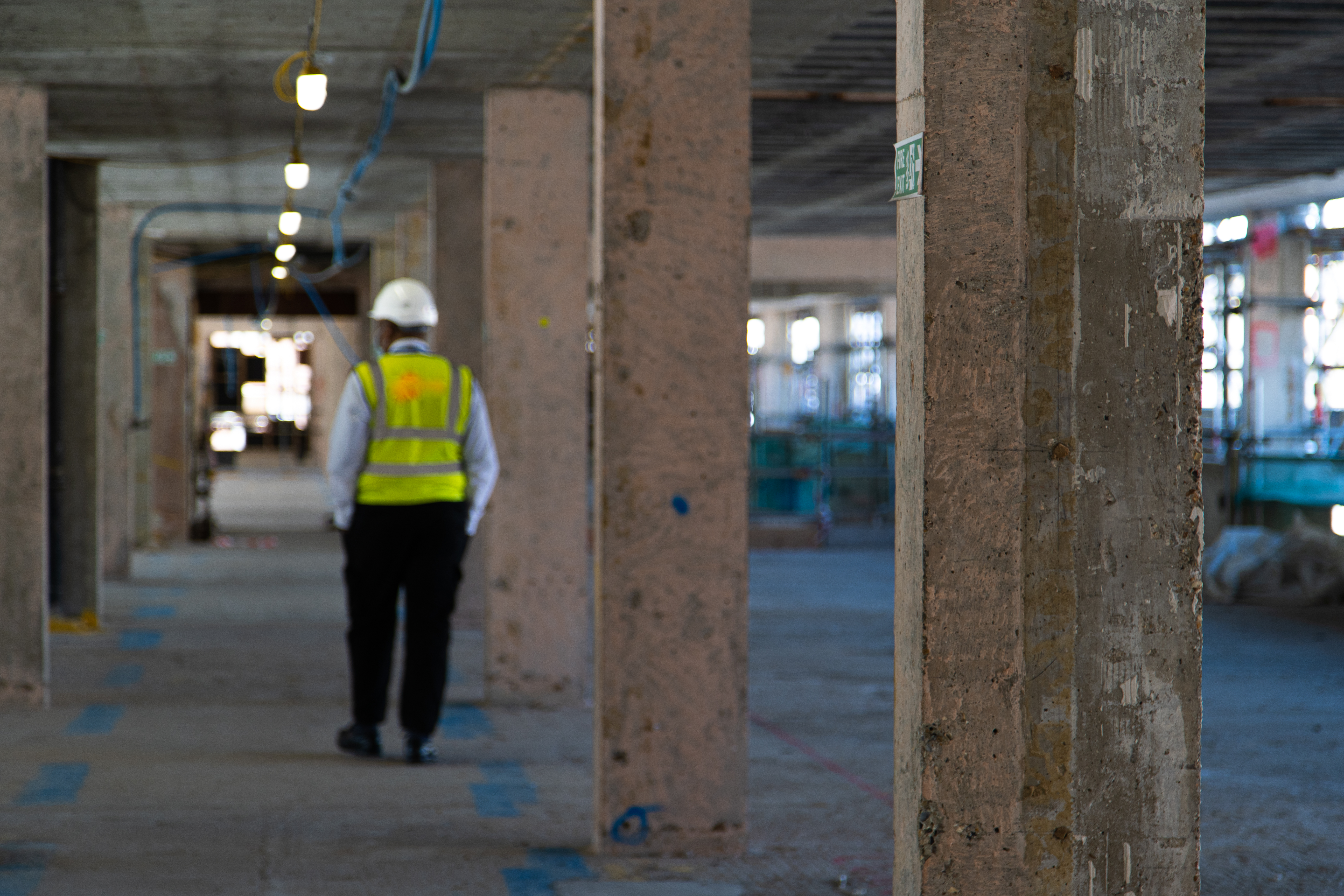 Security colleague in a hard hat and high-visibility vest walking through an industrial building