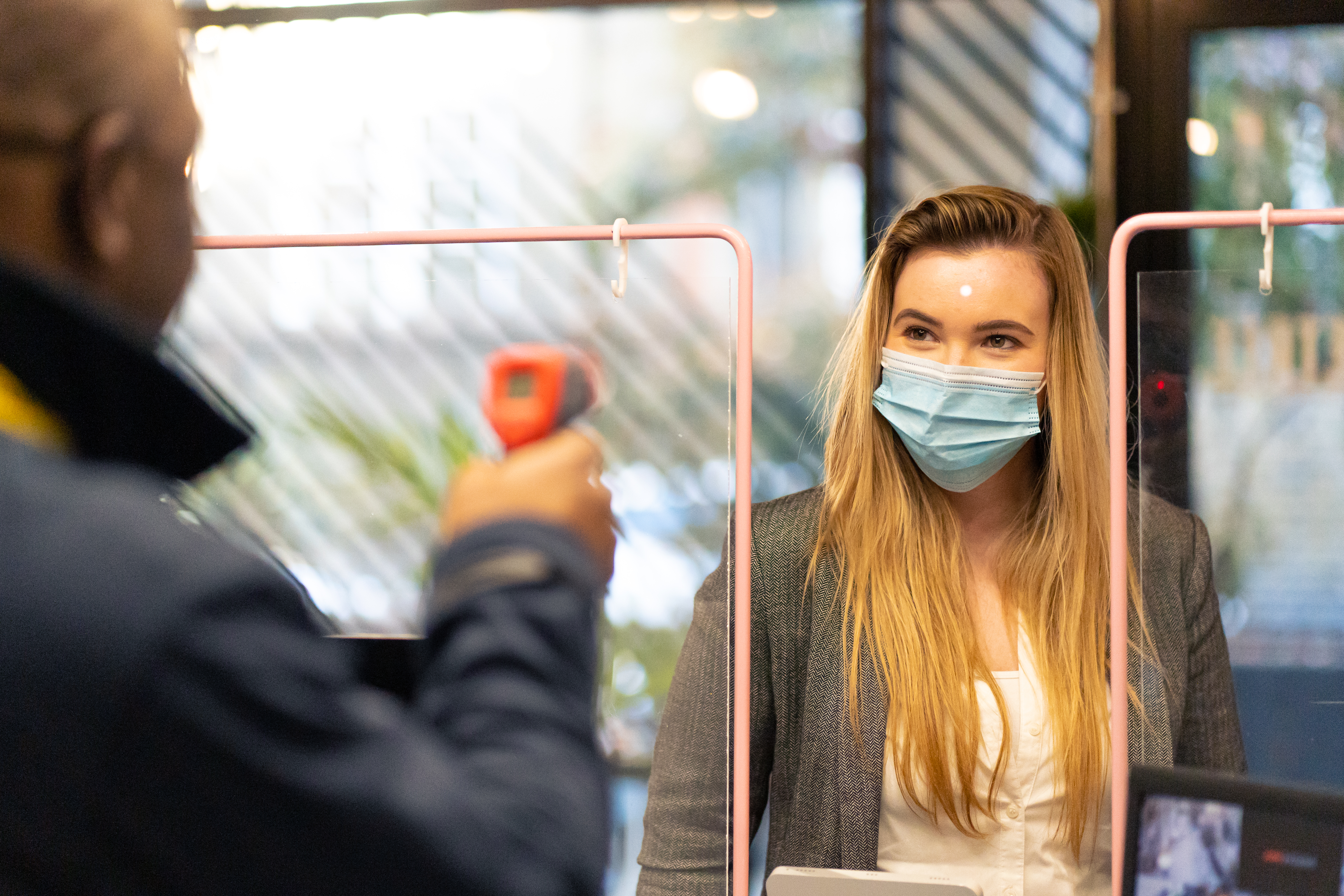 Security colleague carrying out a visitor temperature check at an entrance