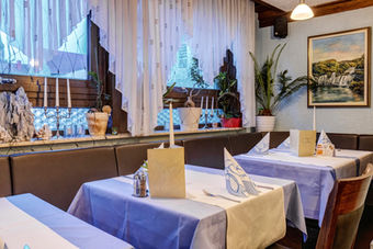 Einige Tische für das Abendessen im blauen Bereich des Restaurants mit Blick auf das Fenster