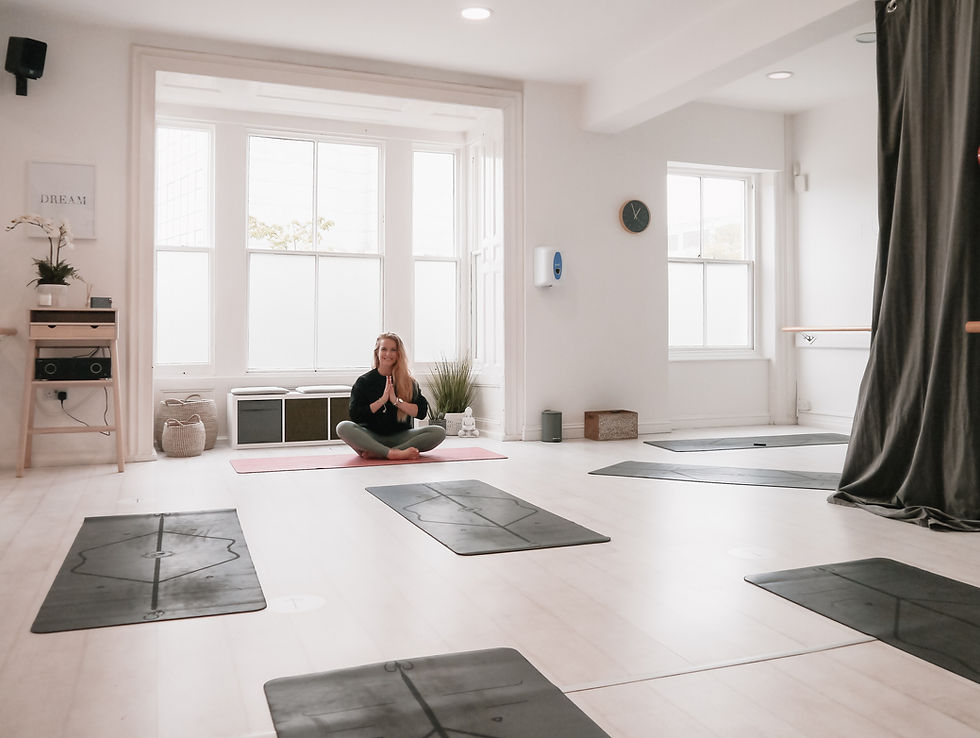 In a serene yoga studio, Ria sits peacefully on her mat, ready for her students to arrive and the class to begin.
