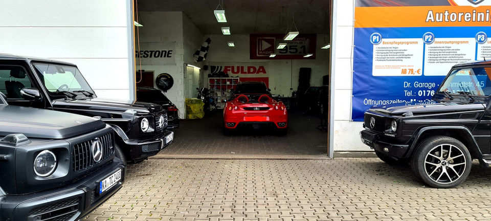 Rotes Auto in der Garage mit Fulda und Bridgestone Werbung. innen Reinigung, Dr. Garage