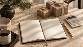 Notebook, calculator and wrapped gifts on a warm stone planning desk.