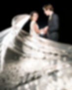 Couple in formal attire facing each other at night with reflective particles on the ground