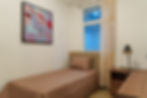 Habitación del apartamento modelo de Eleva Once con cama individual, cubrecama café y mesa de noche.
