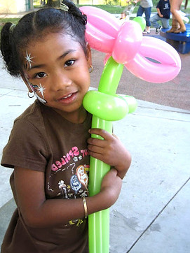 Girl with face paint holding balloon flower