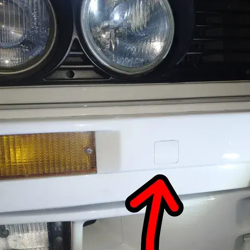 Thumbnail: Close-up of a white car bumper with an orange light and arrow.