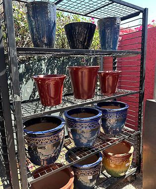 Glossy glazed ceramic pots in blue, red, and tan on shelves.