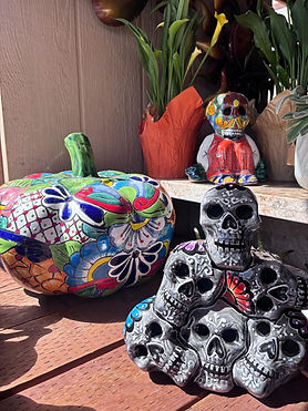 Stacked Talavera skull sculpture beside floral pumpkin.