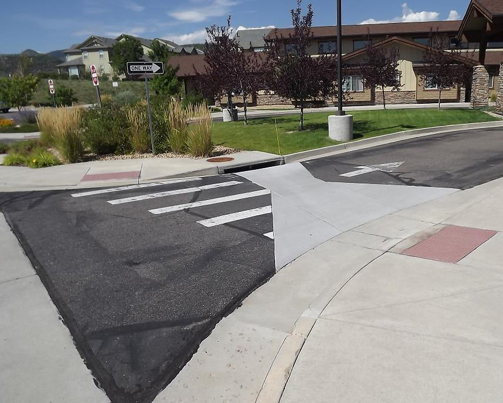 Visibly damaged, repaired, and patched asphalt pavement at handicap crossing.
