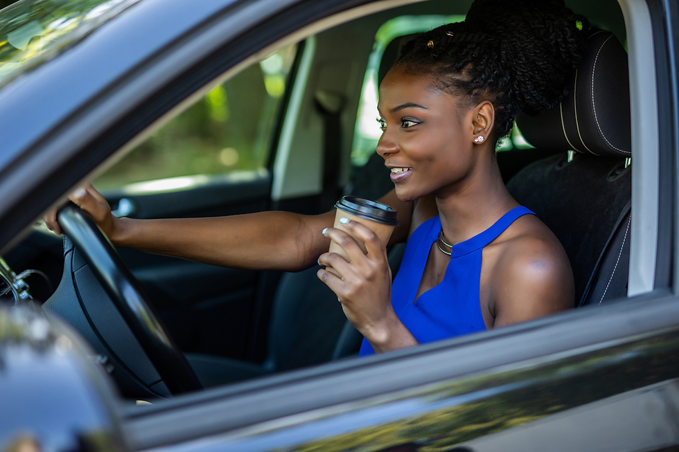 A lady in a car driving with coffee in hand