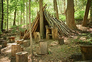 Handmade stick teepee with tree stump seating in a forest._edited.jpg