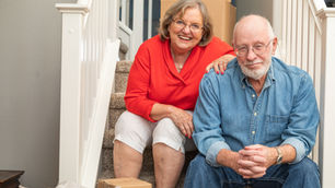 Senior couple on steps surrounded by moving boxes
