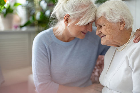 An elderly woman being embraced by her daughter