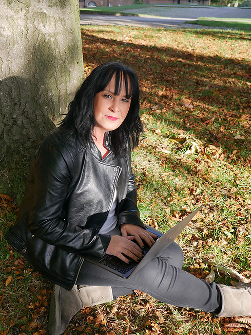 Fiona sat against tree working on laptop