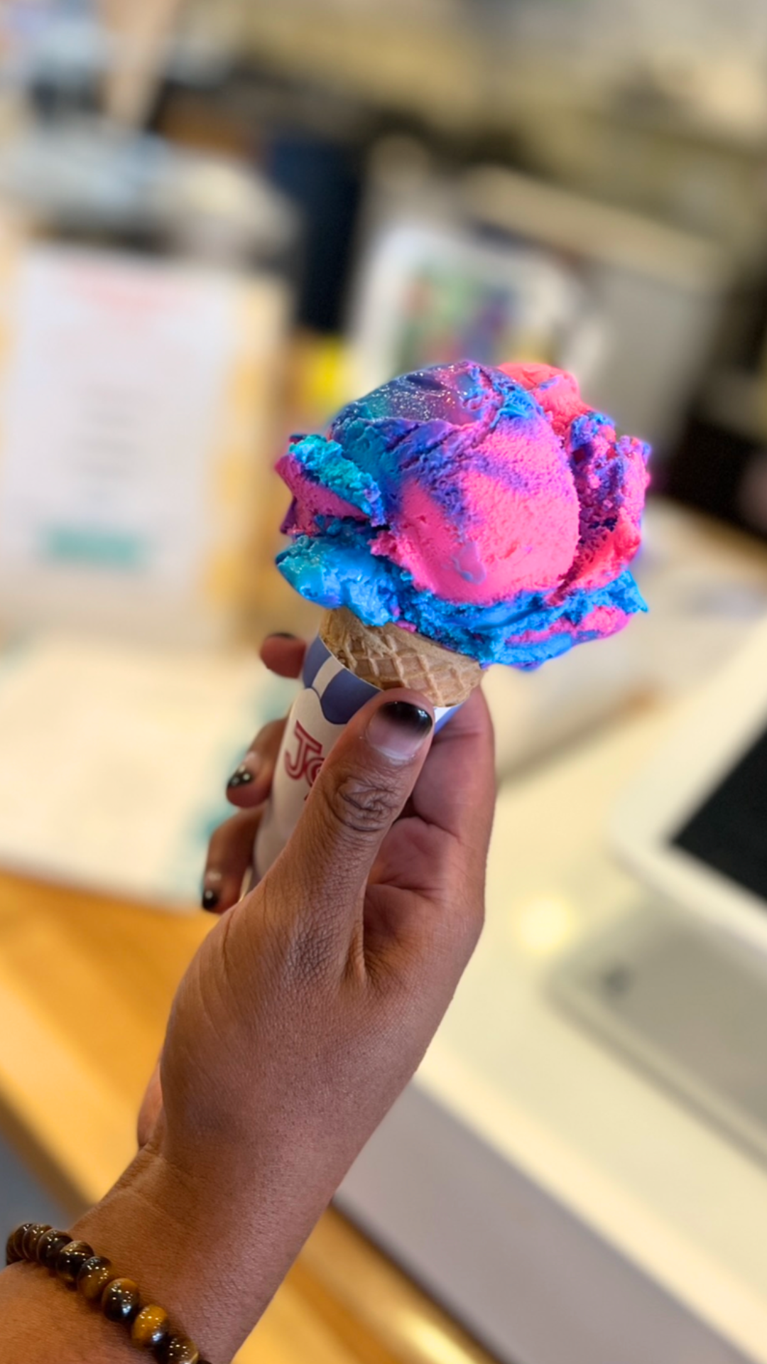 A man holding rainbow ice cream with a black ombre painted nail.