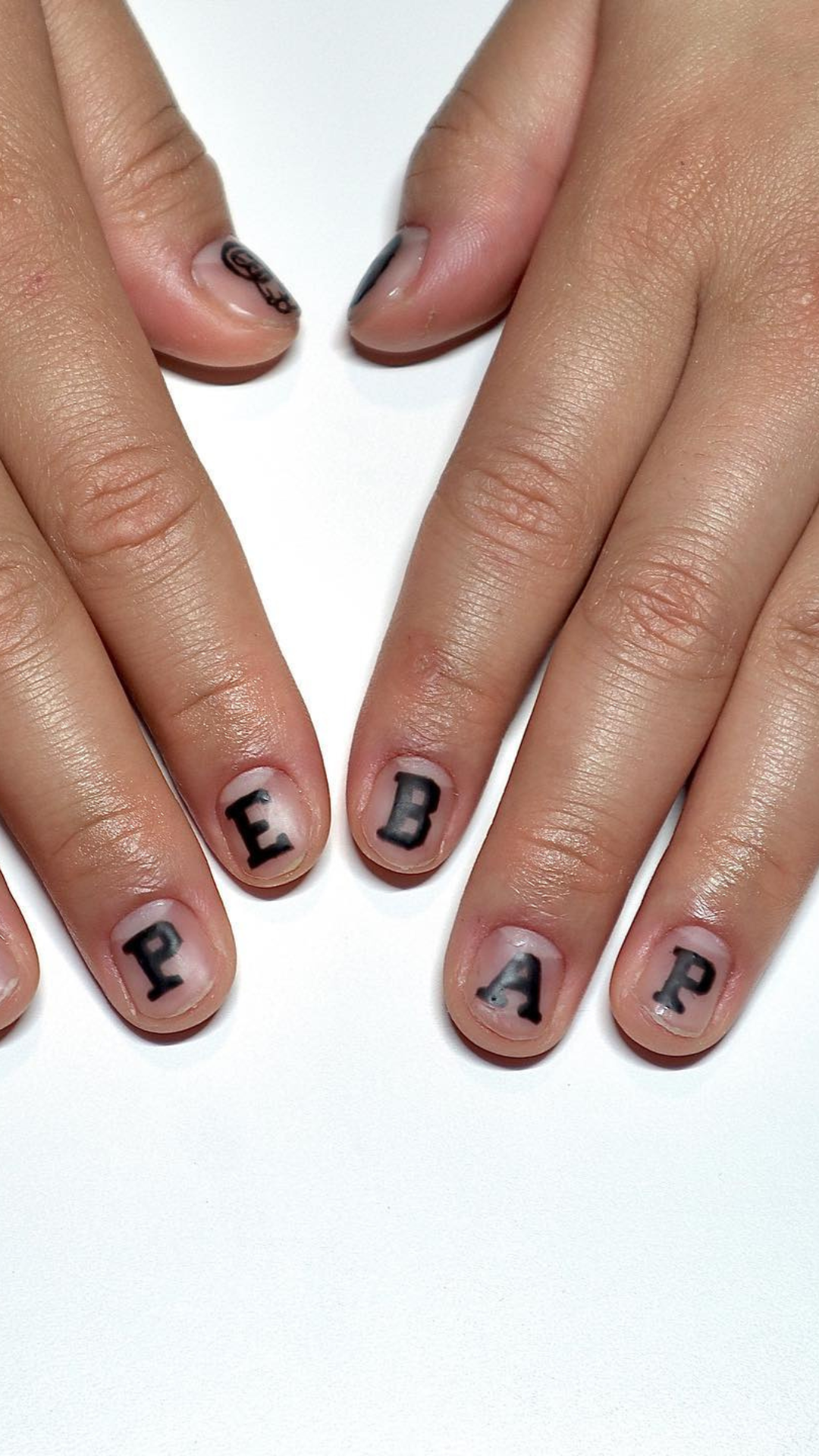 Man with black lettering on a natural manicure. Words read "BAPE".