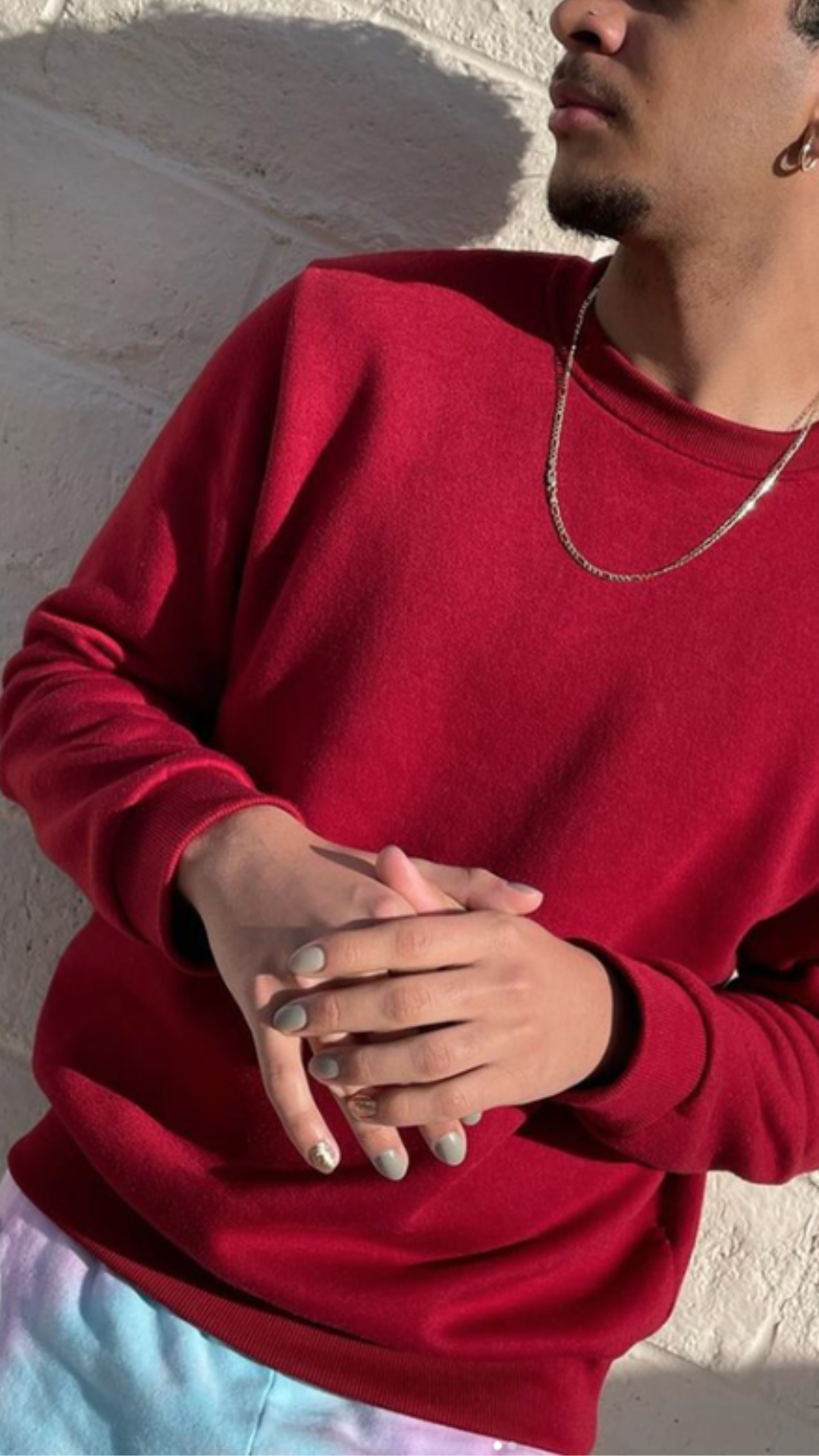 Man with Sage and Silver nail art while wearing a red sweater and fashionable chain.
