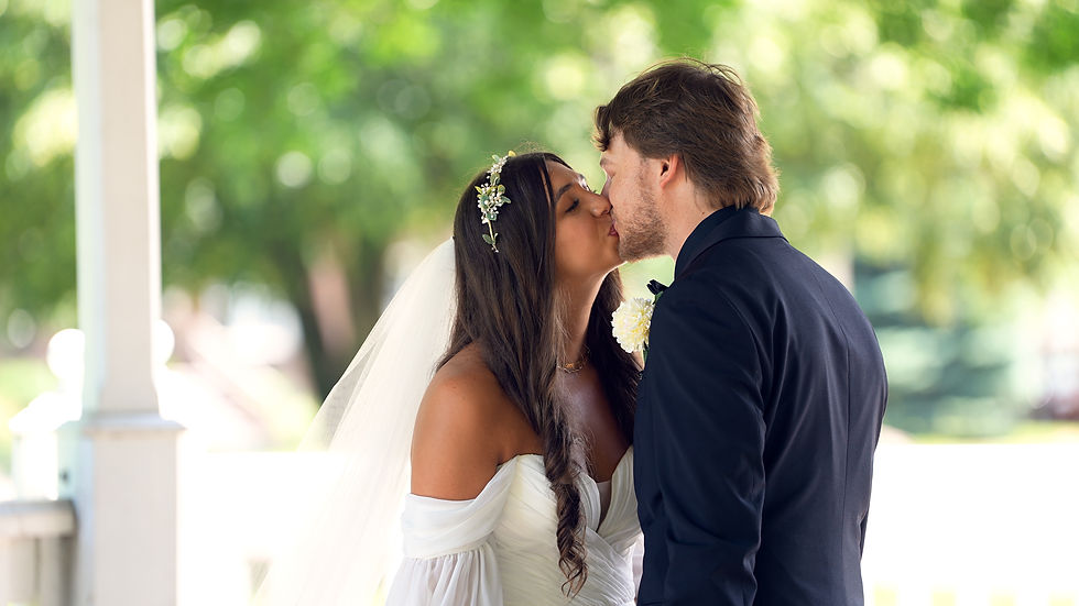 Wedding couple kisses under a white pavilion at Veterans Memorial Park in Fairport Harbor, Ohio during their summer wedding day