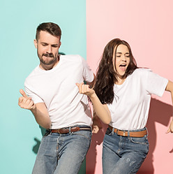 A couple of young funny and happy man and woman dancing hip-hop at studio on blue and pink