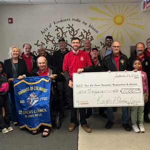 Adults and children displaying a cheque and a banner.