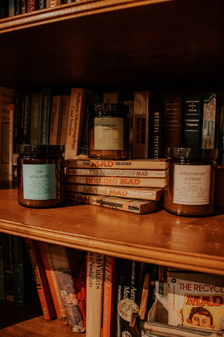 Rustic product photography of a handmade soy wax candles on a bookshelf.