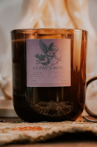 Romantic product photography of a handmade soy wax candle called "Cupid's Bow."