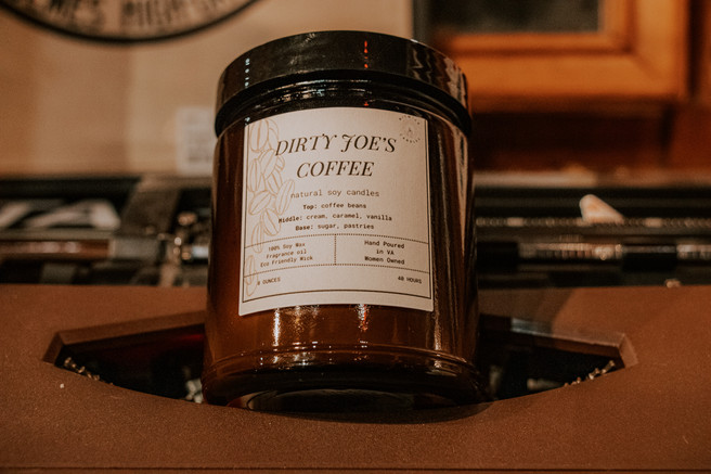 Rustic product photography of a handmade soy wax candle called "Dirty Joe's Coffee" on a typewriter.