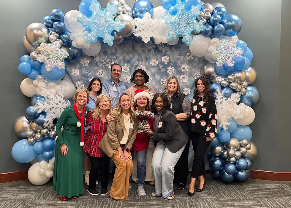 A company christmas picture wth employees standing in front of a snowflake balloon garland and photo backdrop.