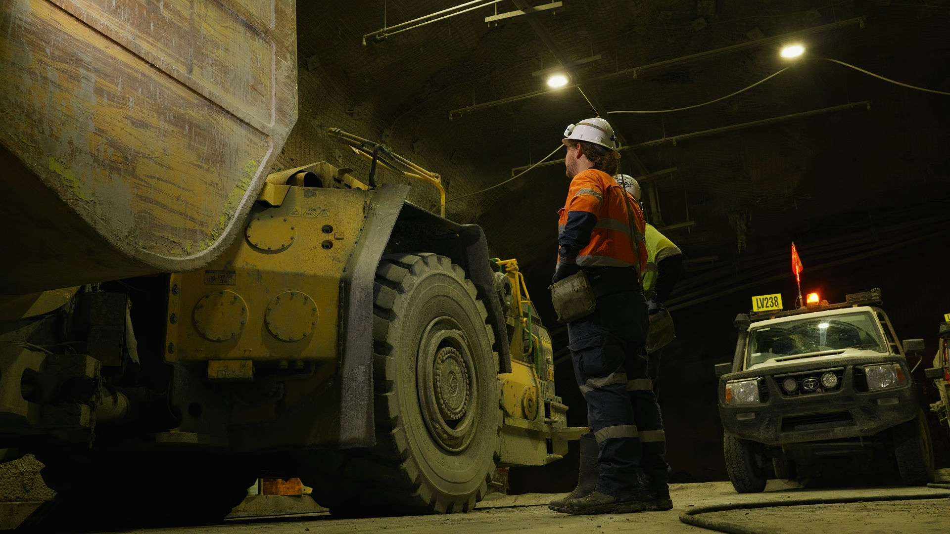 Miners in high-visibility gear next to heavy machinery