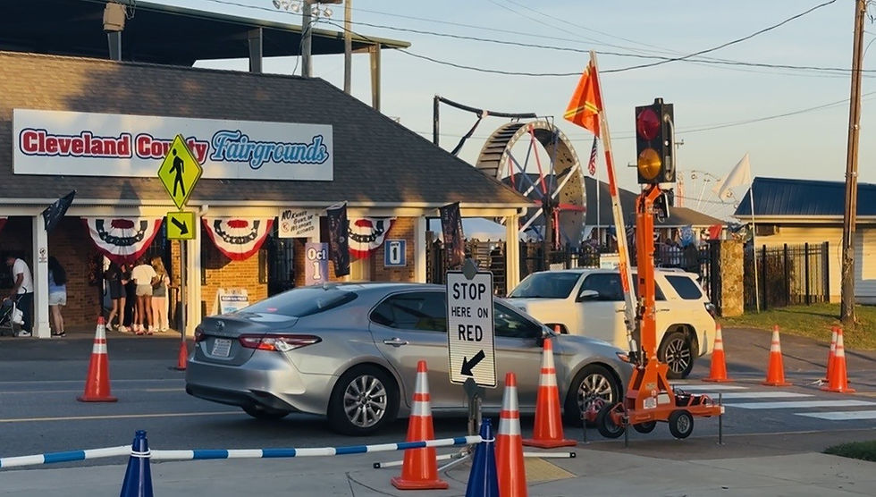 Two vehicles pass one another as the gray car drives underneath the raised orange flag at the front entrance to the Fairgrounds in the eastbound lane. | Chuck Thompson