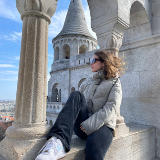 Fishermans bastian: a gril with black pants and a jacket with sunglasses watching the view from the fishermans bastian
