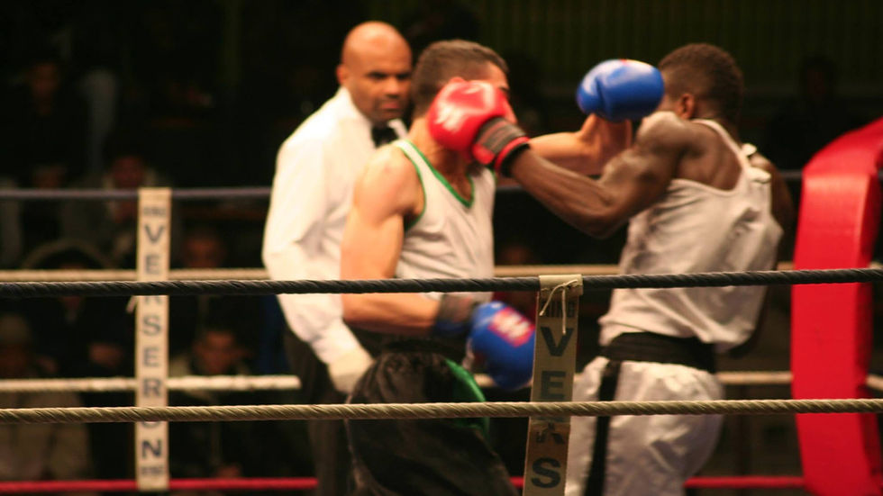 Boxeur amateur qui perd l’équilibre en lançant un crochet sur sac de frappe pendant un entraînement de boxe anglaise.