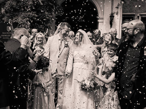 Bride and Groom with friends having confetti Black and white image at Frimley Hall Hotel