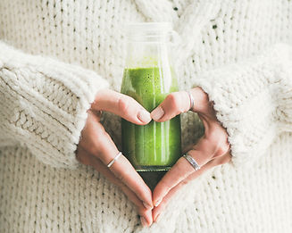 Woman holding green juice representing detox and wellness