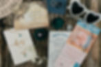 Wedding stationery set with invites, rings, sunglasses, a necklace, and flowers on a wooden table. Text reads "Save the Date" and "Wedfest Events."