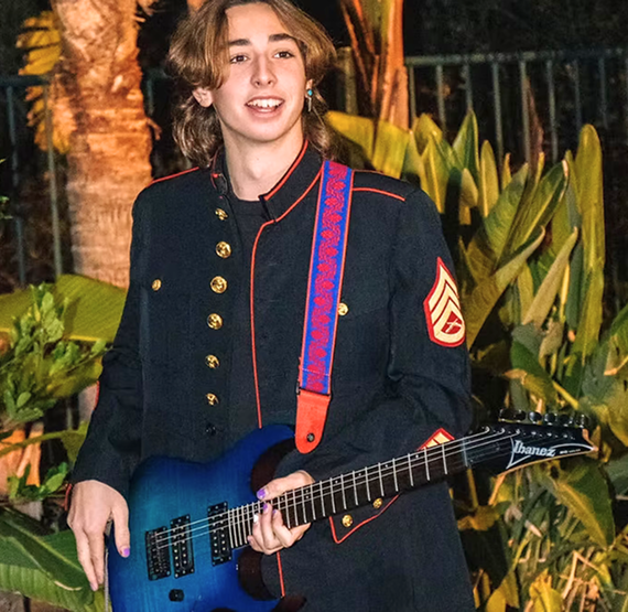 Aiden Green, Repair Technician at Dana Point Music, holding an electric guitar outdoors in Dana Point
